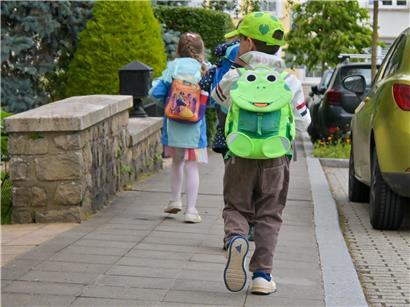 Schulkinder gehen zu Fuß auf dem Gehweg in Petingen, Förderung des sicheren Schulwegs und umweltfreundlicher Verkehr