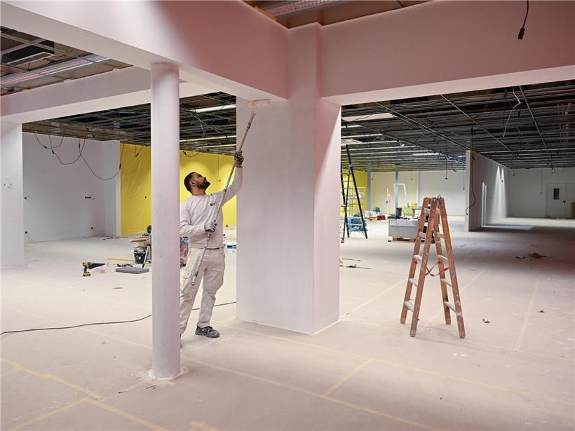 Maler streichen Wände in leerem Raum, Innenausbau fast fertig, bereit zum Einrichten Ende Februar