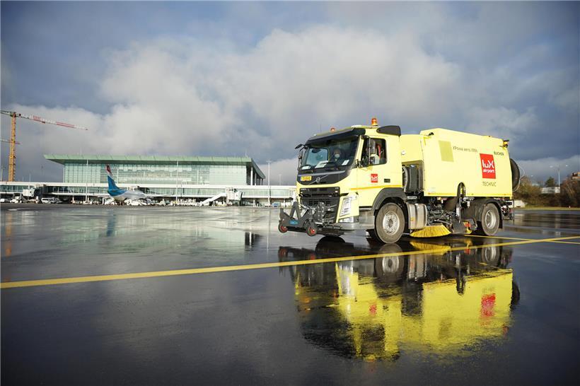 Flughafenmitarbeiter sammeln Glykol mit Kehrmaschinen vom Boden zur umweltgerechten Entsorgung in Kläranlagen