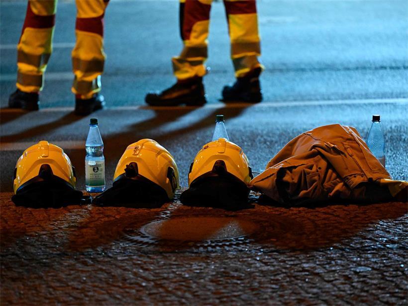 Berliner Feuerwehrleute stehen neben ihren Helmen in der Nähe des Tatorts, an dem eine Person getötet und 16 weitere verletzt wurden