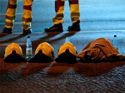 Berliner Feuerwehrleute stehen neben ihren Helmen in der Nähe des Tatorts, an dem eine Person getötet und 16 weitere verletzt wurden