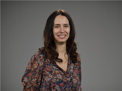 Porträtfoto von Carla Carvalho, lächelnd vor neutralem Hintergrund