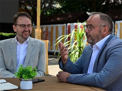 Christian Weis und Carlo Feiereisen lachen bei Gesprächen über Esch, Schifflingen und Anschlussmöglichkeiten zu Lallingen