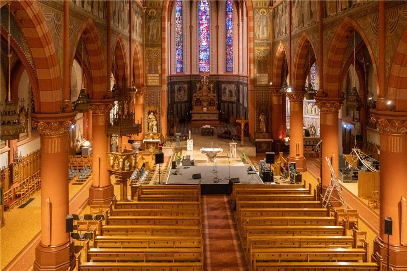 Blick von der Empore auf den Innenraum einer historischen Kirche mit bunten Fenstern und Holzgeländer