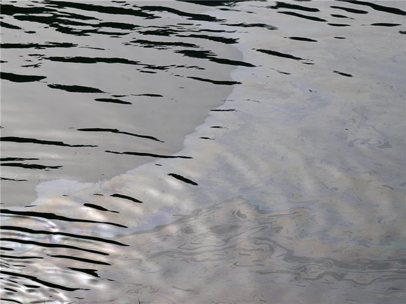 Ölfilm auf der Moseloberfläche bei sonnigem Wetter, sichtbare Umweltverschmutzung im Flusswasser
