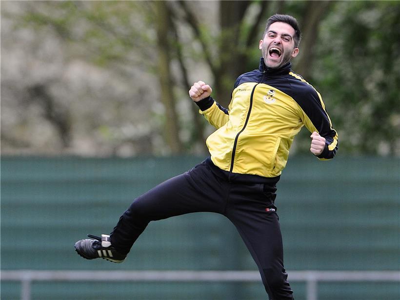 Trainer lacht entspannt in Kamera, zeigt lockere und humorvolle Atmosphäre während Fotoshooting eines sportlichen Coachs