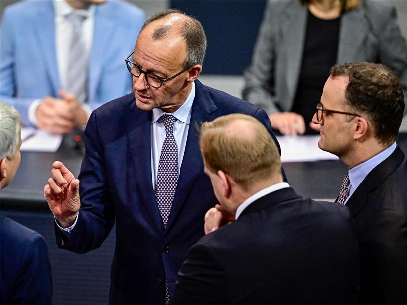 Deutscher Kanzler Friedrich Merz zeigt im Bundestag den knappen budgetären Spielraum zwischen Daumen und Zeigefinger