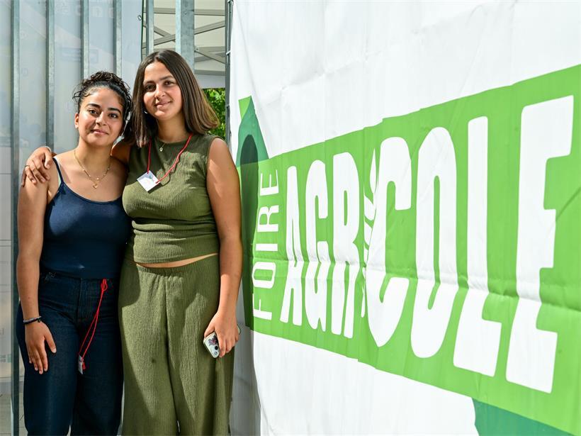 Schulklasse macht Video-Umfrage auf der „Foire agricole“ Zineb und Safâ, Ettelbrücker Schülerinnen, lächeln zusammen vor einer Schule in Ettelbrück, Luxemburg
