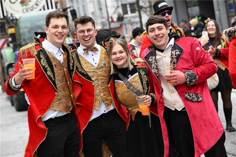 Karnevalsfans feiern ausgelassen bei regnerischem Wetter mit bunten Kostümen und guter Stimmung