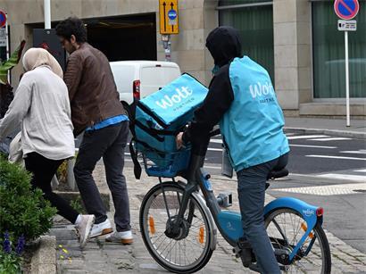 Wolt-Kuriere auf Motorrollern und Leihfahrrädern liefern Essen in der Stadt, repräsentativ für den Covid-Lieferdienst-Trend
