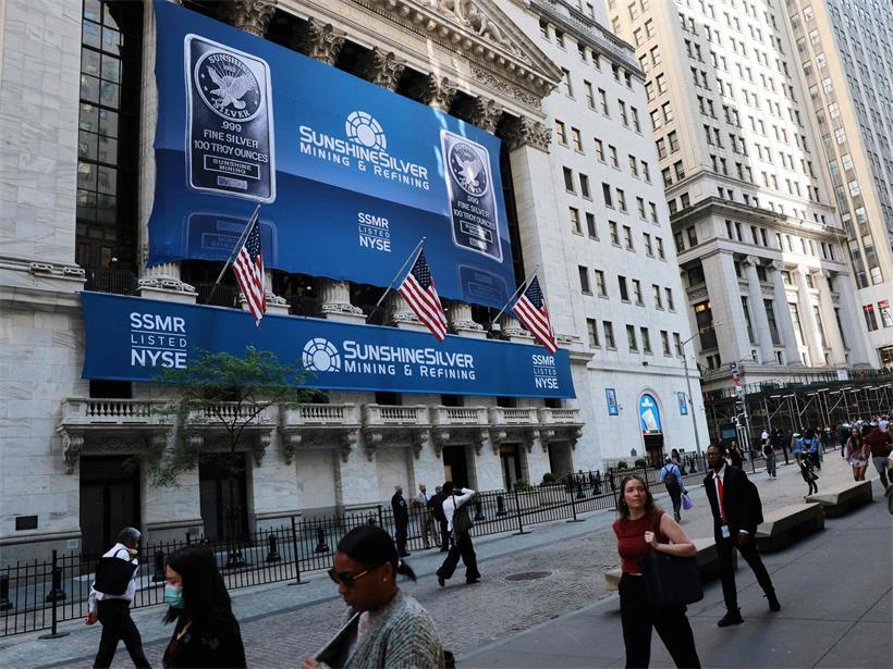 Wall Street mit Finanzgebäuden symbolisiert US-Wirtschaftsmacht und wachsender Staatsschuldenberg im Hintergrund
