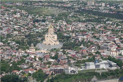 Panoramablick auf die georgische Hauptstadt Tiflis mit historischen Gebäuden und moderner Stadtlandschaft bei Sonnenuntergang