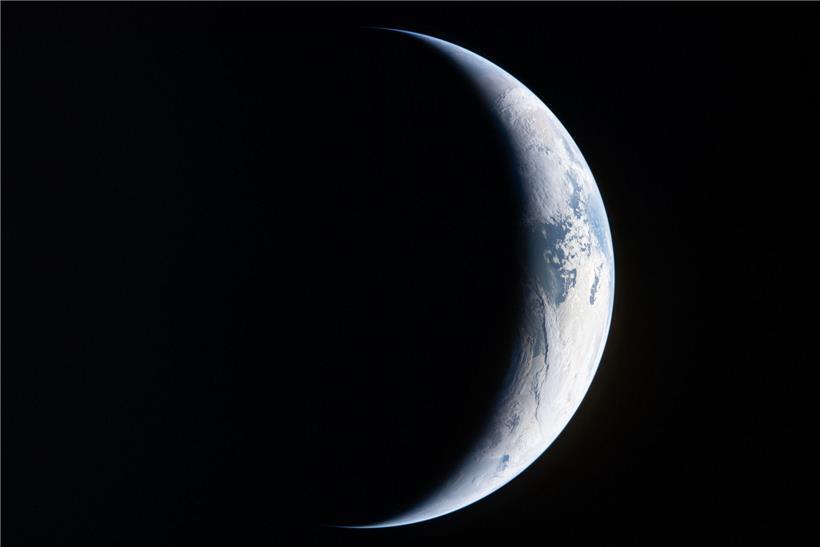 Blick aus dem Orion-Raumschiff der Artemis-II-Mission auf einen Erdstreifen vor dem schwarzen Weltraumhintergrund