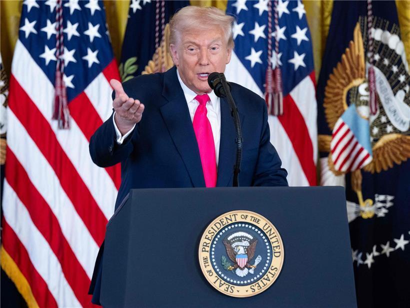 Donald Trump mit ernster Miene vor Weltkarte, symbolisch für imperialistische Weltherrschaftsfantasien