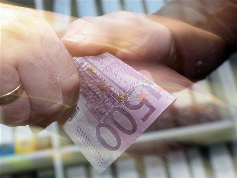 500-Euro-Schein wird von einer Hand zur anderen übergeben, Symbol für Geldtransfer und Finanztransaktion