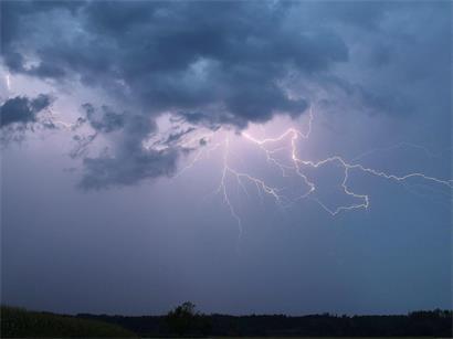 Ein Blitz zuckt bei einem Sommergewitter am abendlichen Himmel