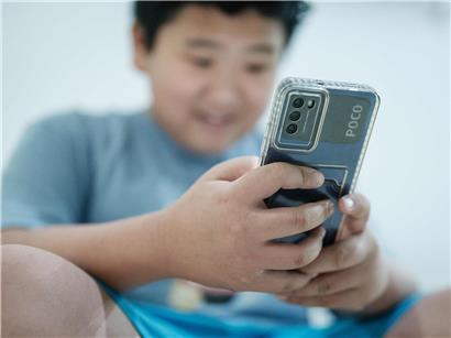 11-jähriger Junge lacht und nutzt Social-Media-Plattform auf Smartphone, fröhlich und aktiv online unterwegs