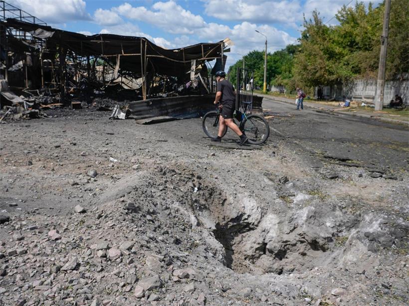 Ein Mann geht nach einem russischen Raketenangriff in Kiew (Ukraine) an einem Raketenkrater auf dem Marktplatz der zerstörten Stadt vorbei