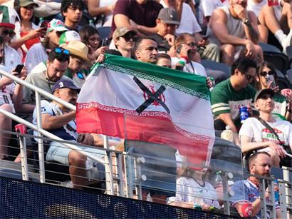Zuschauer mit iranischer Flagge und Protest-X beim Fußballspiel Iran gegen Neuseeland