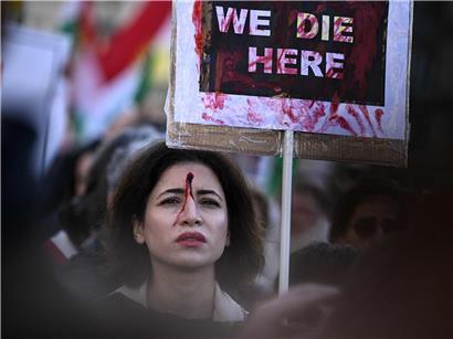 Demonstrantin mit rotem Fleck auf Stirn hält Plakat bei Solidaritätskundgebung für Iraner in Paris, Januar 2026 (Archivbild)