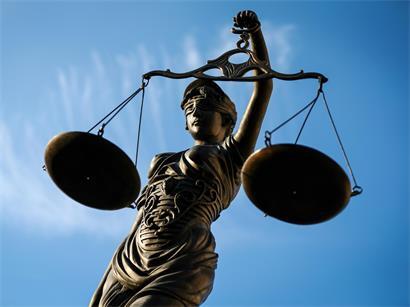 Eine Statue der Justitia hält eine Waage in ihrer Hand