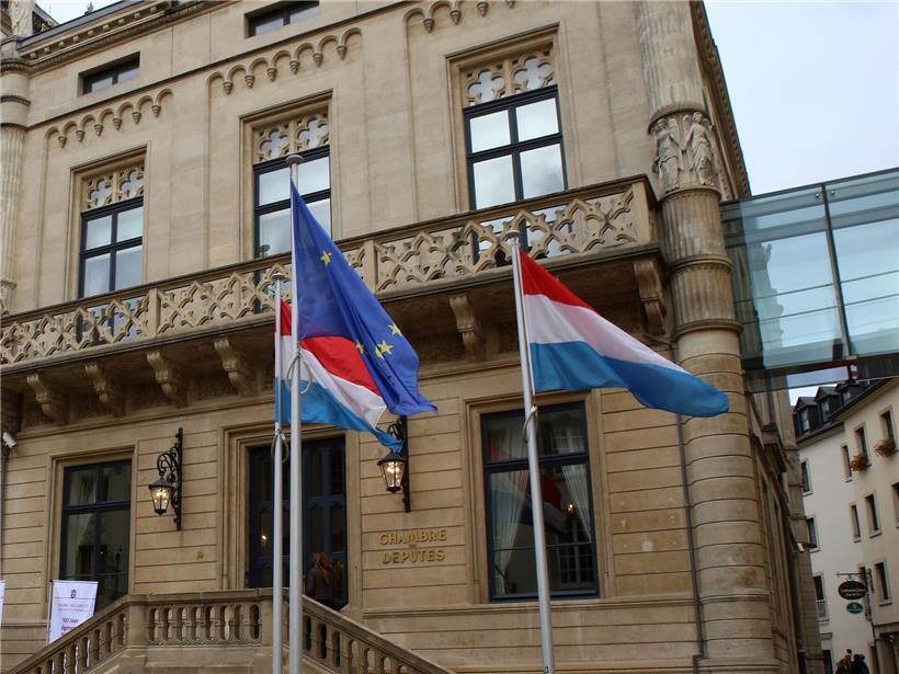 Fahnen wehen vor dem historischen Parlament in Luxemburg-Stadt bei klarem Himmel