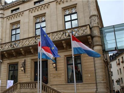 Fahnen wehen vor dem historischen Parlament in Luxemburg-Stadt bei klarem Himmel