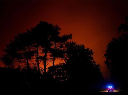 Feuerwehrleute fahren um einen brennenden Wald herum und überwachen dabei einen Waldbrand in der Nähe eines Wohngebiets bei Lege-Cap-Ferret im Südwesten Frankreichs