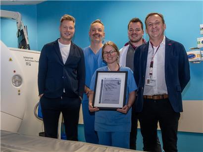 Mann freut sich über erfolgreiche Zertifizierung mit Urkunde in hellem Büro, Symbol für beruflichen Erfolg