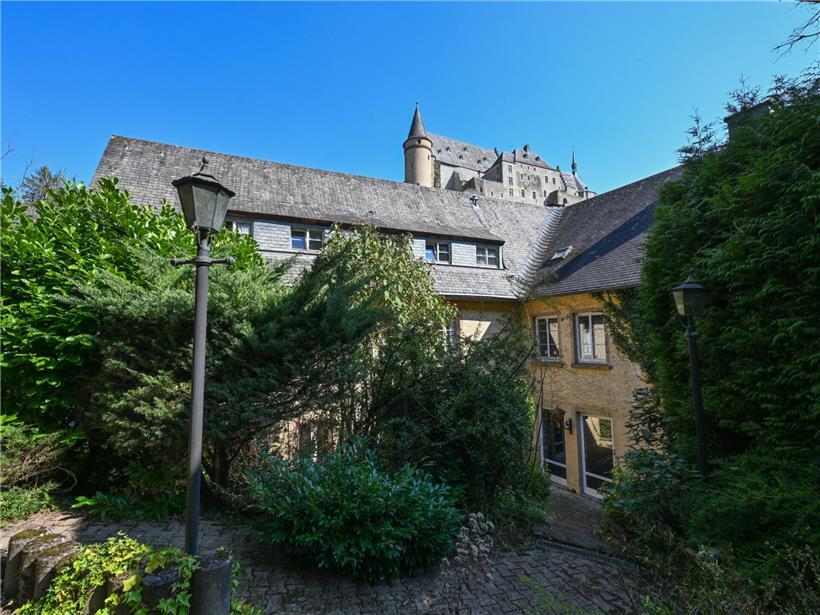 Garten mit grünen Pflanzen und Sitzbereich, Panoramablick auf Landschaft und blauen Himmel im Hintergrund