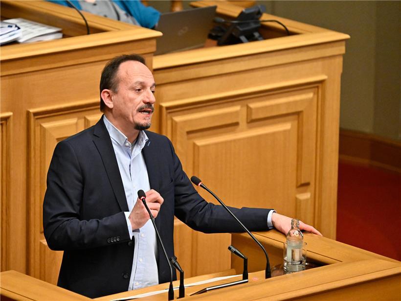 Marc Baum, Linken-Politiker, spricht bei einer Sitzung, hält Gesetzesvorschlag in der Hand