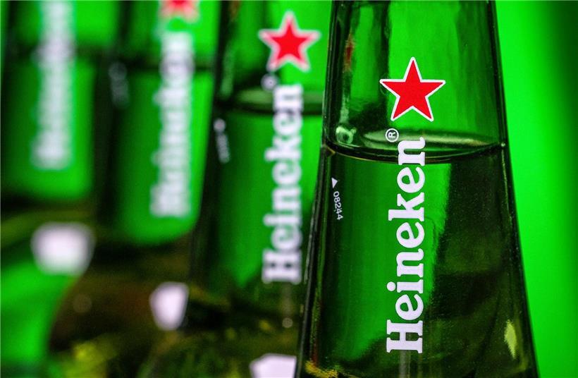 Heineken-Logo vor Fabrikgebäude, Symbol für geplanten Stellenabbau und Kostensenkung beim Bierhersteller