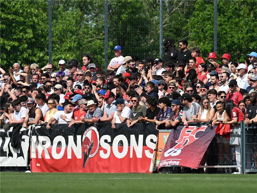 Fans im gut gefüllten Gästeblock feiern bis zur 56. Minute mit Fahnen und Trikots bei Fußballspiel