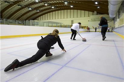 Curling-Spieler mit Stein auf Eisbahn in Luxemburg, symbolisiert 48 aktive Curling-Lizenzen im Land