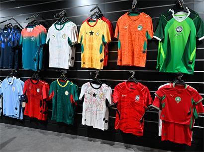 Trikots verschiedener WM-Teilnehmer im Laden in Luxemburg kaufen, Fußball-Fanartikel und WM-Merchandise sichtbar