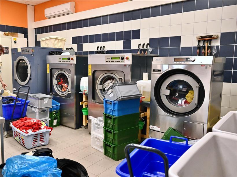 Joëlle Hinna lächelt vor einem Wäschekorb mit frisch duftender, sauberer Wäsche im hellen Raum