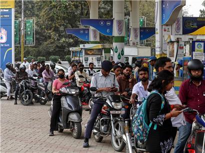 Menschen in Varanasi, Indien, warten mit Motorrädern an einer Tankstelle auf Treibstoffversorgung