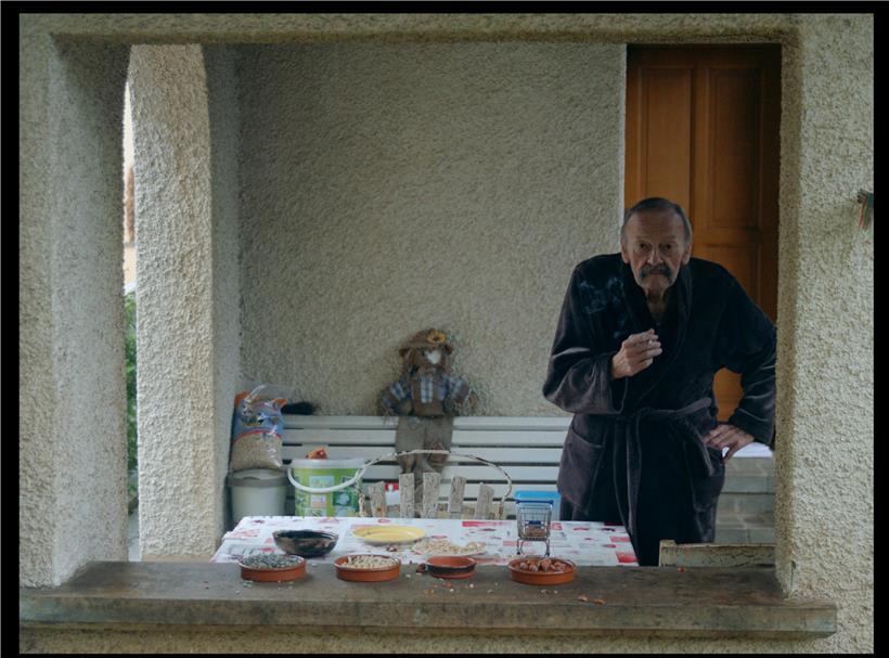 Mann in ländlicher Landschaft aus Bäumen, Hügeln und Mauern in Fränz Hausemers „Terre Rouge – Topographie du Poète“