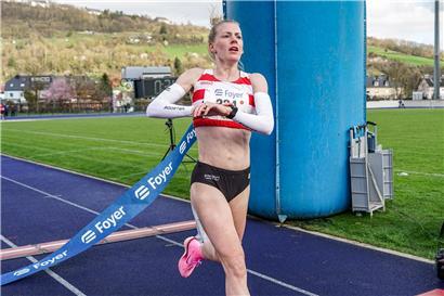 Jenny Gloden gewinnt den Zehn-Kilometer-Lauf der Damen, siegreich beim Wettkampf mit Laufmedaille und Sportkleidung