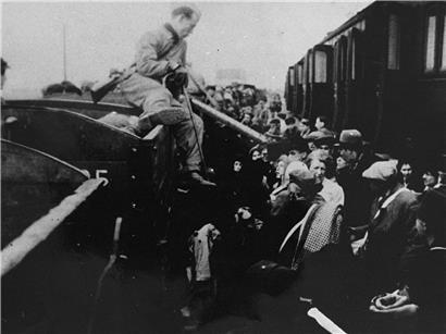 Jüdische NS-Opfer werden aus dem Ghetto Litzmannstadt in das Vernichtungslager Chelmno transportiert. Am Bahnhof Kolo werden sie aus einem geschlossenen Personenzug in einen Zug mit offenen Waggons umgeladen.