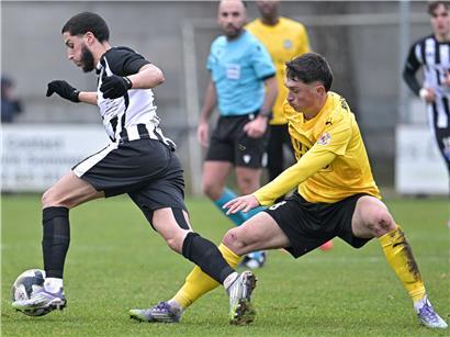 Eldin Rastoder in gelbem Trikot beim Angriff auf dem Fußballfeld, kämpft um den Ball vor dem Tor