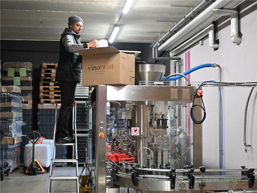 Kellermeister Marc füllt Drehverschlüsse in moderne Weinabfüllanlage während Produktionsprozess in Weinkellerei