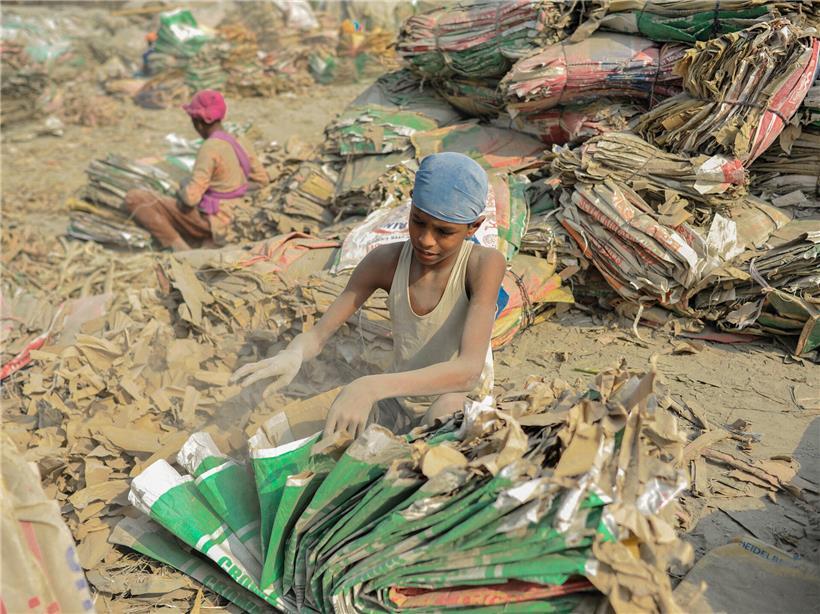 Kinder sortieren inmitten von Zementstaub gebrauchte Zementsäcke am Ufer des Surma-Flusses in Bangladesch
