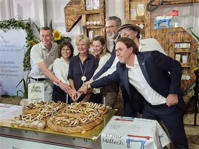 Landwirtschaftsministerin Martine Hansen schneidet Geburtstagskuchen mit Fäirmellech-Partnern bei Feier