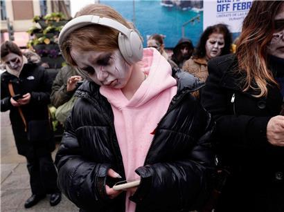 Zombies mit realistischer Maske starren auf Smartphones bei Horror-Happening in Madrid auf belebter Straße