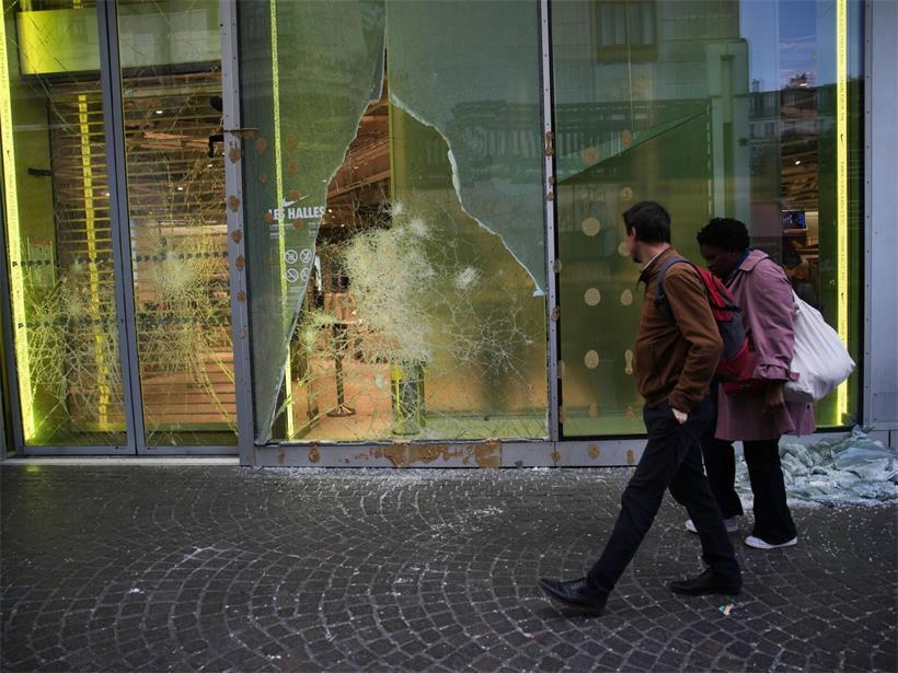 Menschen gehen an einem geplünderten Geschäft in Paris vorbei