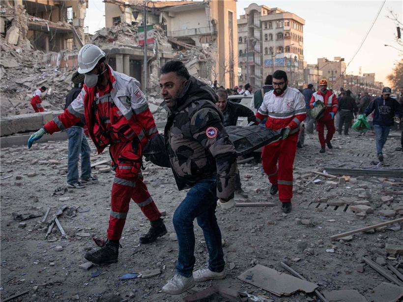 Rettungskräfte tragen nach Luftangriff in Teheran ein Todesopfer weg, Einsatz bei Katastrophenhilfe und Notfallrettung