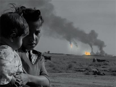 Operation Enduring Freedom: Ein irakisches Mädchen hält 2003 seine Schwester in der Nähe einer brennenden Ölraffinerie in den Armen