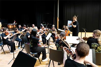 Orchesterprobe mit Musikern, Geigen und Dirigent in einem Konzertsaal, klassische Musik live üben