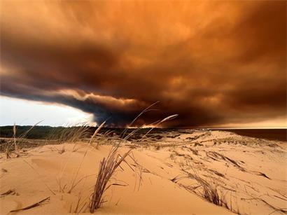 Rauchwolken von den Waldbränden südöstlich des Badeortes Lacanau-Ocean (hinten, r.) verdunkeln den Himmel, während sie über die Dünen am Nordstrand hinwegziehen